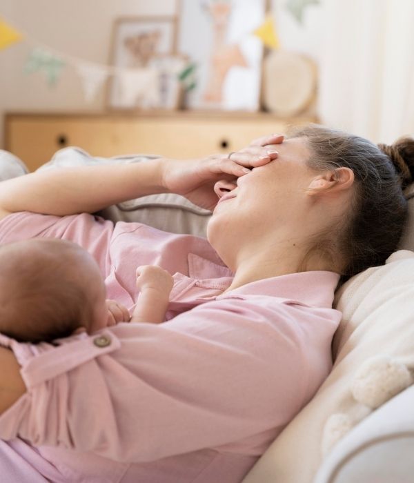 Tired new mother holding her baby during postnatal recovery