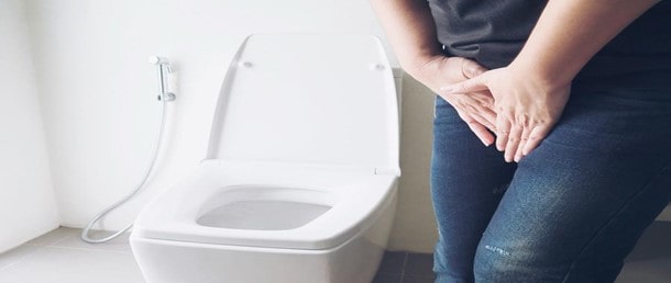Women holding bladder next to toilet